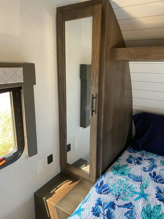 Compact RV rental bedroom featuring a bed, full-length mirror, storage, and practical outlets.. Forest River Salem Cruise Lite 2021