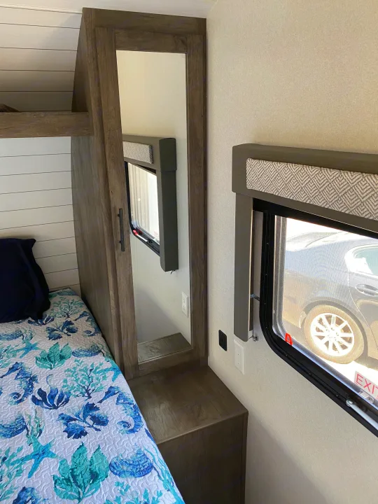 RV rental bedroom: Bed with blue marine quilt, full-length mirror, and two windows. A cozy interior ready for travel.. Forest River Salem Cruise Lite 2021