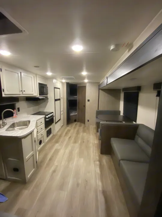 Spacious and modern RV rental interior featuring a full kitchen, comfortable dinette seating, and light wood-look flooring.. Open Range Open Range 2021
