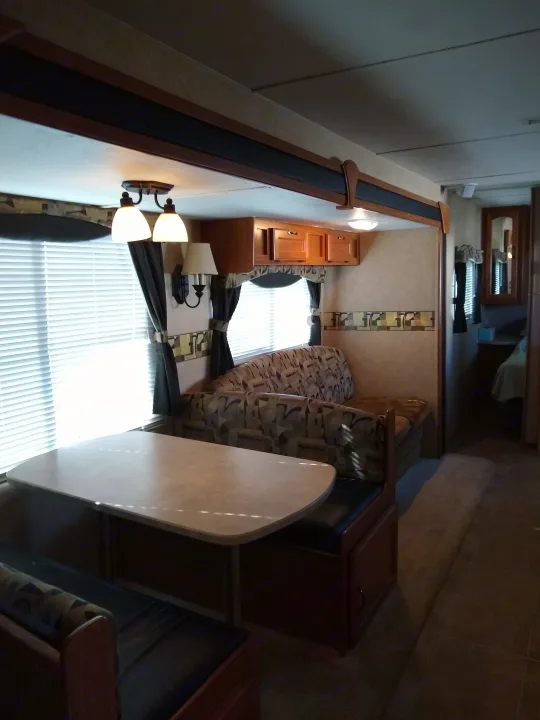 RV rental interior features a cozy dinette, patterned couch, and overhead storage, ideal for comfortable travel.. Frontier Hyperlite 28RBH 2008