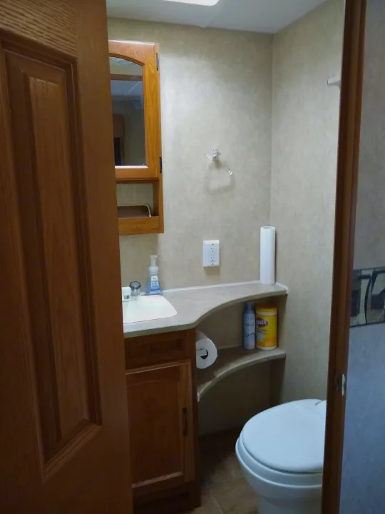 A clear view into a clean, functional RV rental bathroom, highlighting the sink, toilet, and practical shelf storage.. Frontier Hyperlite 28RBH 2008