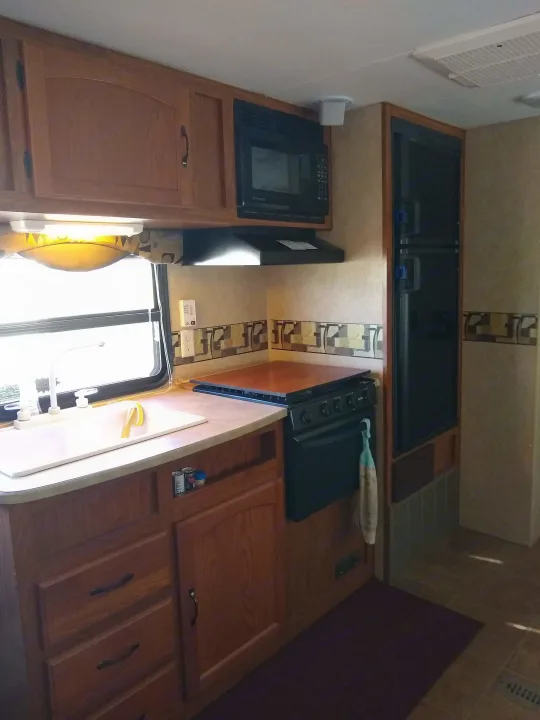 Bright RV rental kitchen with sink, microwave, oven, and refrigerator. Functional design for mobile living.. Frontier Hyperlite 28RBH 2008