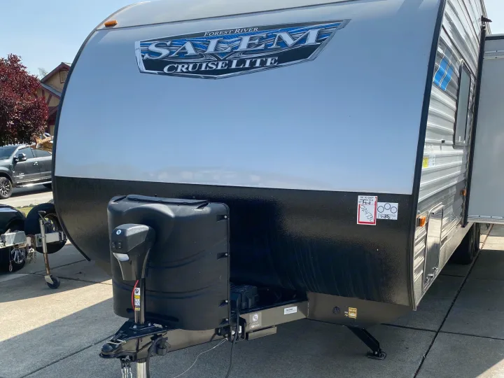 Front view of a silver and black Salem Cruise Lite travel trailer, ready for an RV rental. Shows hitch and propane tanks.. Forest River Salem Cruise Lite 2021
