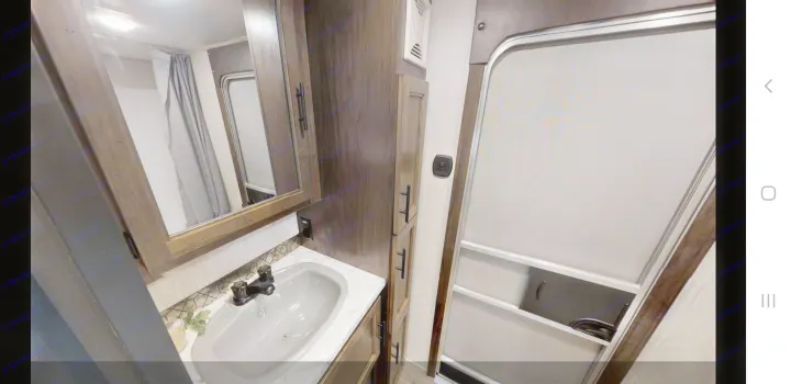 RV rental's compact bathroom features a vanity with gray sink, mirror, storage, and shower with screen door.. forest river cherokee 39ca 2019