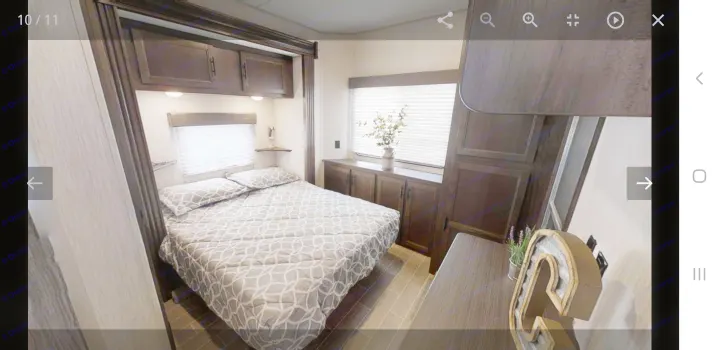 Comfortable RV rental bedroom with a patterned bed, overhead cabinets, and bright windows, providing cozy accommodations for your trip.. forest river cherokee 39ca 2019
