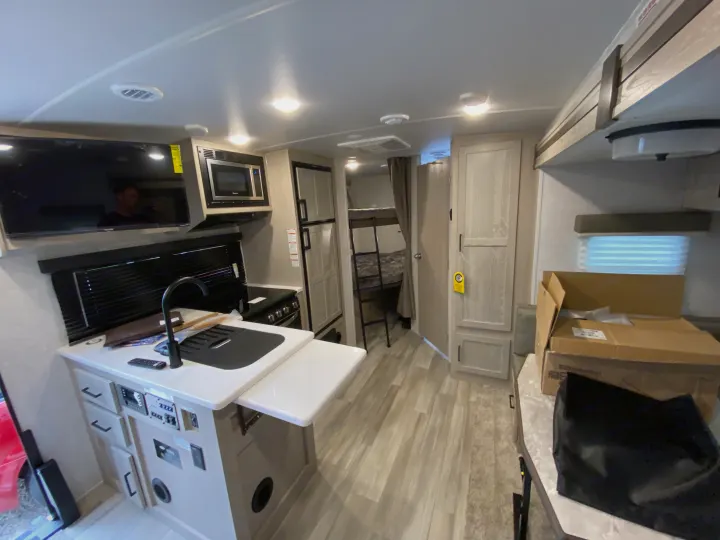 Spacious RV rental interior: kitchen with sink/stove, TV, fridge, and bunk beds. Modern camper living space.. Forest River Mini-Lite 2021