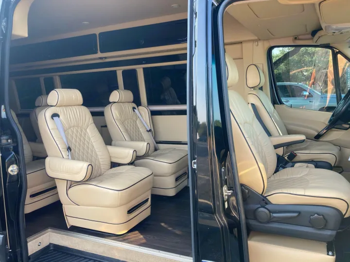 Luxurious RV rental interior with cream leather captain's chairs, wood floor, and overhead storage.. Mercedes-Benz Sprinter 2015