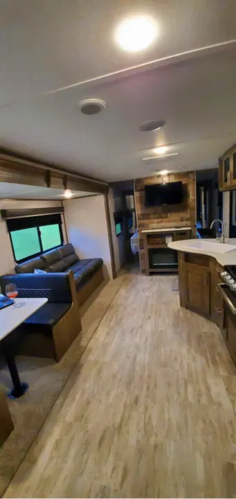 Modern **RV rental** interior showcasing a comfortable living area, dinette, fully equipped kitchen, and entertainment options.. Dutchmen Aspen Trail 26BH 2021