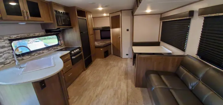 Spacious RV rental interior with kitchen, dining booth, sofa, and bunk beds. Perfect for travel.. Dutchmen Aspen Trail 26BH 2021