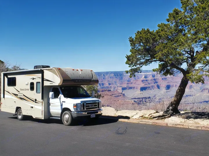 An RV rental, a beige Winnebago Minnie Winnie, parked at a scenic Grand Canyon overlook with stunning canyon vistas.. Winnebago Minnie Winnie 2019