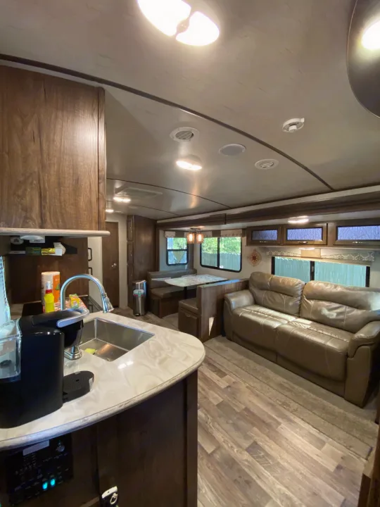 View inside an RV rental: modern kitchen, dining booth, and comfortable living area with a leather sofa.. Other Other 2018