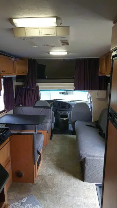 RV rental interior: A view of the living space with a dining booth, kitchen area, and front cabin, ideal for travel.. Ford Majestic 2007