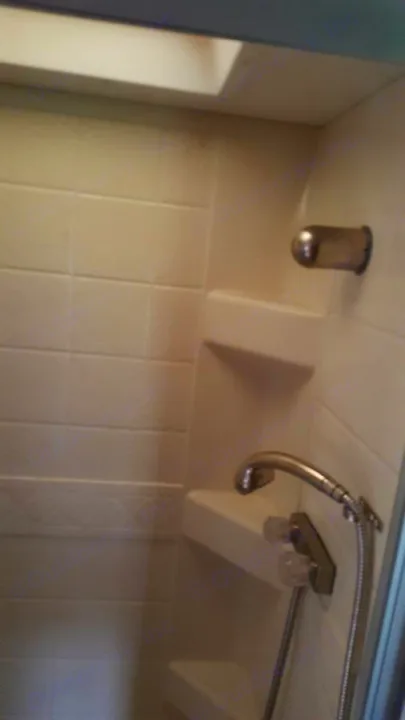 Inside an RV rental, a compact shower stall with white tiled walls, built-in shelves, and a handheld shower.. Ford Majestic 2007