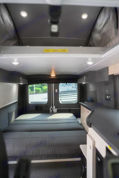 RV rental camper van interior. Features a large bed, counter, windows, and bright lighting. Ideal for road trips & adventures.. Ram Pleasure Way 2019