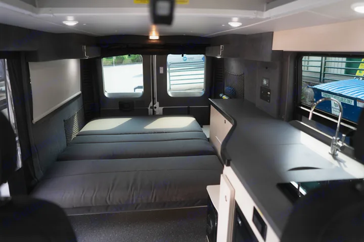 Experience a comfortable rv rental interior featuring a large bed at the rear and a well-appointed kitchen counter with a sink.. Ram Pleasure Way 2019