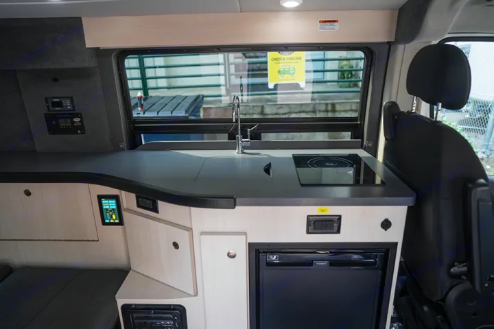 RV rental interior: A modern camper kitchen featuring a sink, induction cooktop, fridge, and wall-mounted controls.. Ram Pleasure Way 2019
