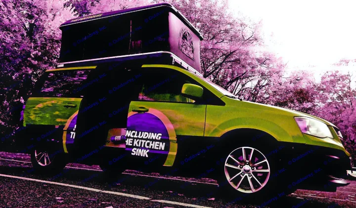 This unique green pop-top camper van is an excellent rv rental choice, featuring "The Penthouse" and "Including the Kitchen Sink" text.. Dodge Grand Caravan 2014