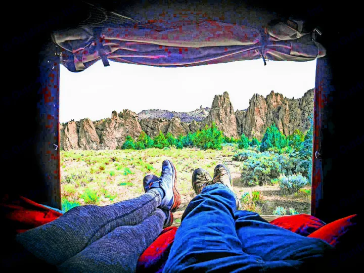 Relaxing inside an RV rental with legs propped up, enjoying a stunning scenic view of rocky mountains and trees.. Dodge Grand Caravan 2014