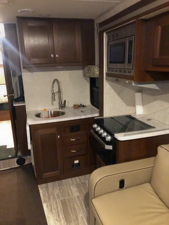 Inside an RV rental, discover a well-appointed kitchen featuring a sink, microwave, and stove with wood cabinetry.. Forest River forester 2019