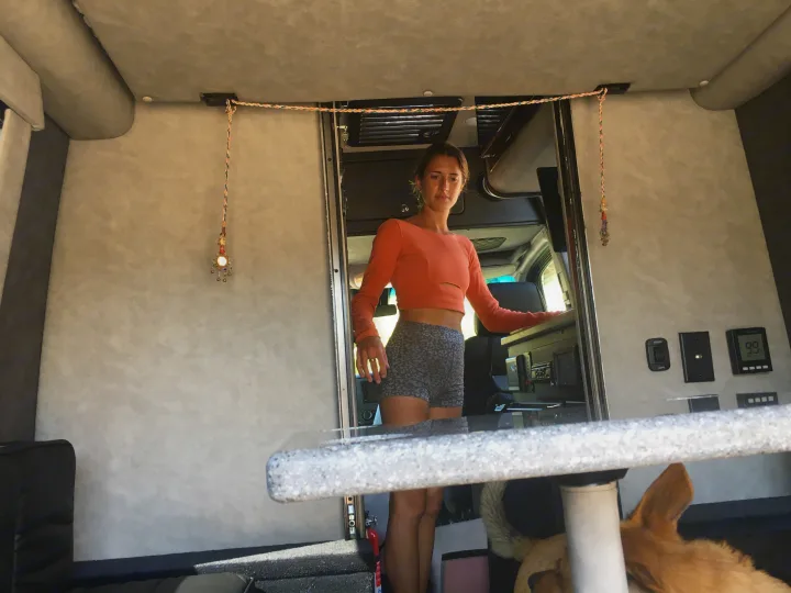 Enjoying the spacious interior of an RV rental, with a woman and her dog relaxing amidst custom decor and accessible controls.. Mercedes-Benz Sprinter 2018