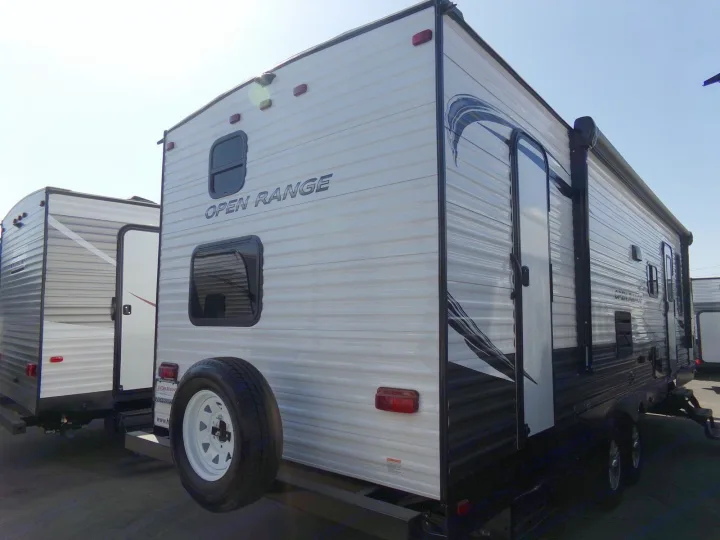 Side view of a white "OPEN RANGE" travel trailer with a visible spare tire, perfect for your next RV rental.. Open Range Open Range 2020