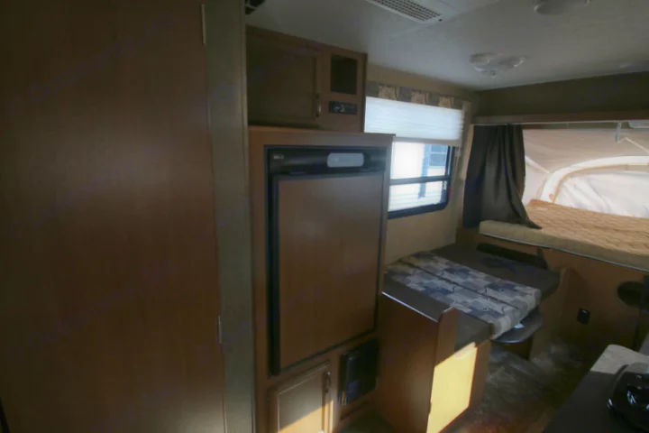 RV rental interior featuring a refrigerator, dining area with patterned cushions, and a cozy pop-out bed.. Starcraft Launch 2014