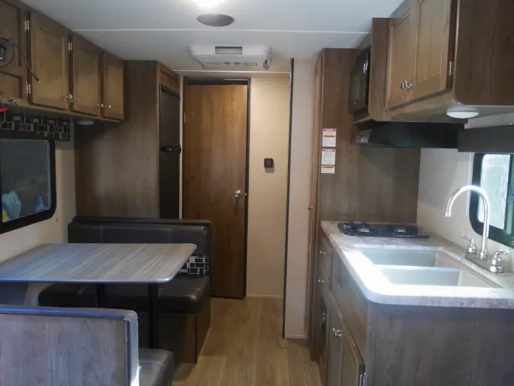RV rental interior showing a kitchen with sink, stovetop, dining area with table, and refrigerator.. Coleman Other 2018