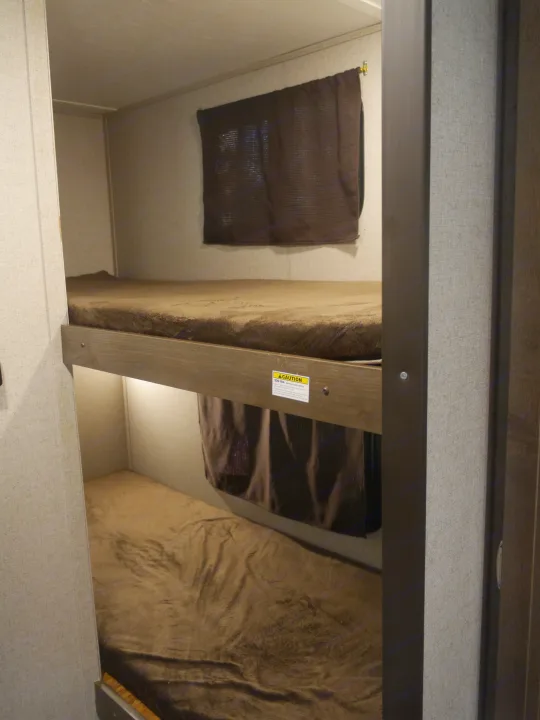 Cozy RV rental bunk beds with brown bedding & privacy shades. Note 300 lb max capacity sticker on top bunk.. Coleman Other 2018