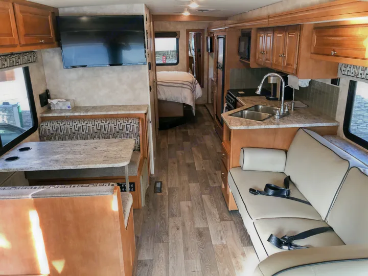 Spacious RV rental interior featuring a full kitchen, dinette, comfortable sofa, and a bedroom area.. Winnebago Vista 2018