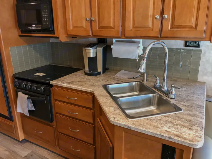 Well-equipped RV rental kitchen with stove, microwave, dual sink, and coffee maker on granite-look counters.. Winnebago Vista 2018