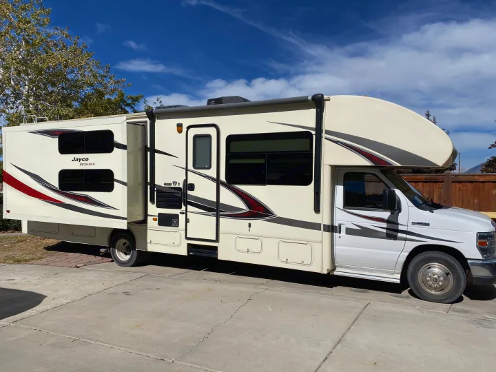 Cream Jayco Redhawk Class C RV rental with extended slide-out, parked on a concrete driveway on a sunny day.. Jayco Redhawk 2017