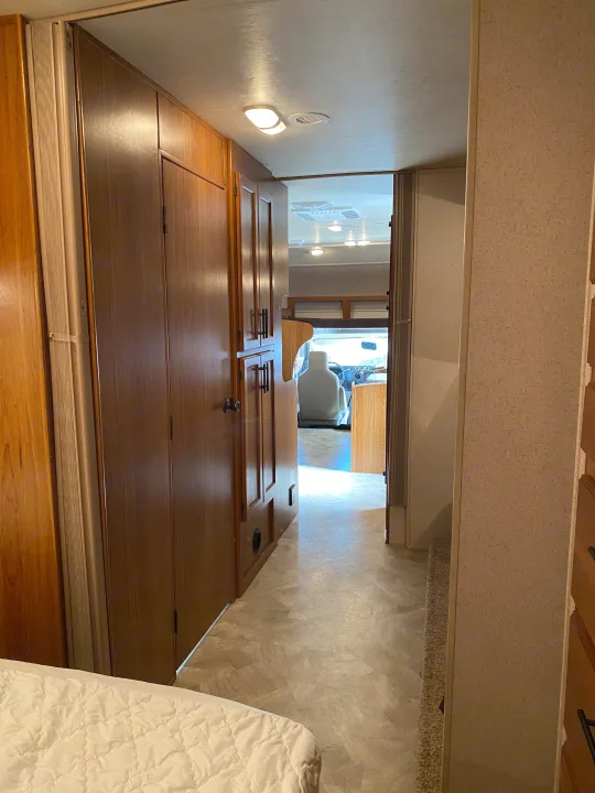 RV rental motorhome interior: Hallway from sleeping area, with wood cabinetry, leading to the driver's cockpit.. Jayco Redhawk 2017