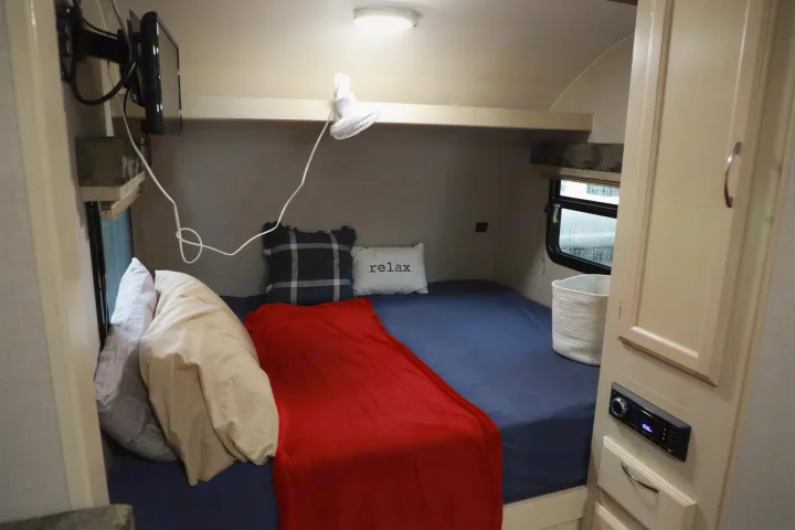 An RV rental's cozy bedroom: compact bed, TV, fan, and storage unit with stereo.. Other Other 2018