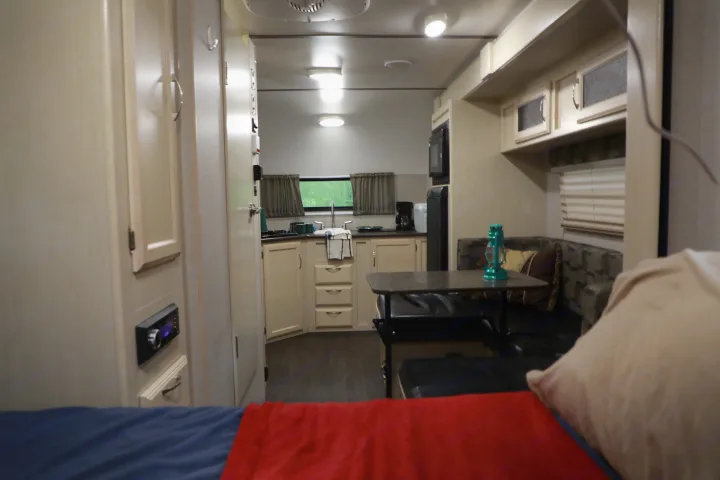 RV rental interior: kitchen, dining booth, and bed in foreground. A compact, functional living space perfect for travel.. Other Other 2018