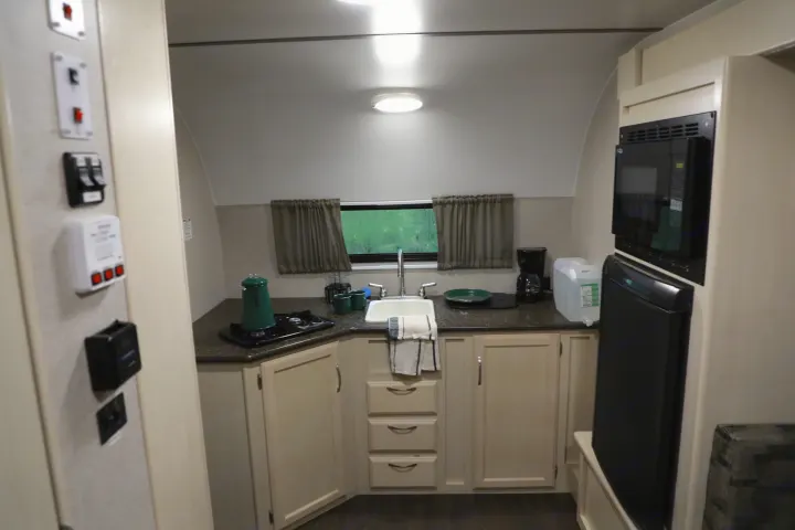 Compact and well-equipped RV rental kitchen featuring a sink, microwave, fridge, and stove for comfortable travel.. Other Other 2018