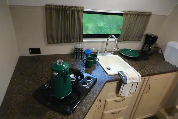 This RV rental kitchen features a sink, two-burner stove, coffee maker, and window with a nature view.. Other Other 2018