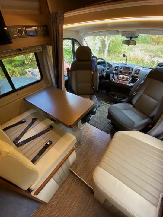 RV rental interior: A cozy dinette with seatbelts and the front cabin's dashboard and seats.. Winnebago Travato 2018
