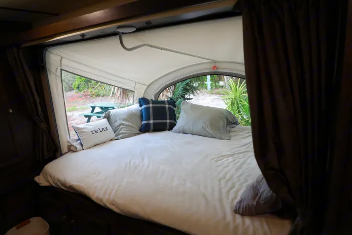 Relax in this comfortable RV rental bed with a scenic outdoor view. Inside a camper with large windows.. Starcraft Other 2018