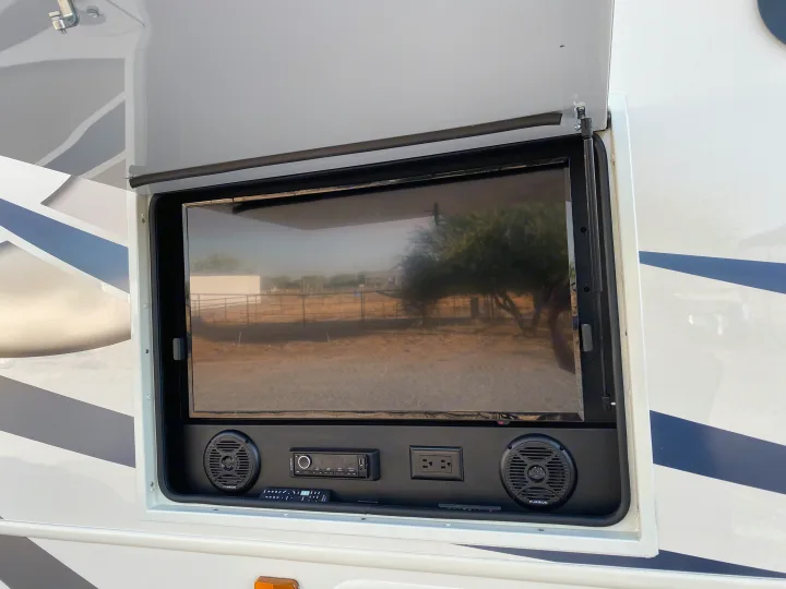 An open RV compartment reveals a complete outdoor entertainment system with TV, speakers, and stereo, great for rv rental trips.. Entegra Coach Other 2021