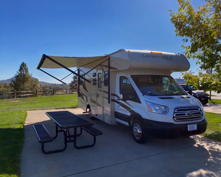 Sunny RV rental setup with extended awning and picnic table at a scenic campsite.. Other Other 2020