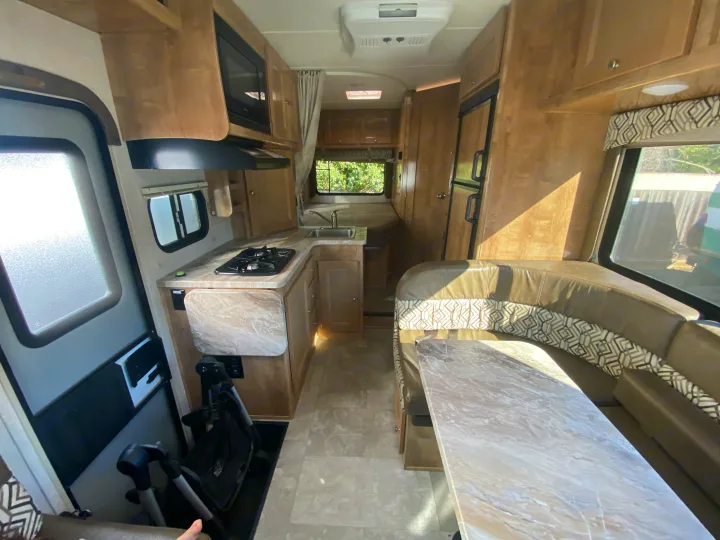 Bright RV rental interior featuring a kitchen with stove/sink, U-shaped dinette, fridge, and ample storage.. Other Other 2020