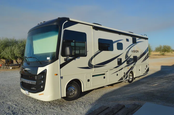 A bright white Entegra Vision motorhome, ideal for an RV rental adventure, sits on gravel under a clear sky.. Entegra Coach Other 2021
