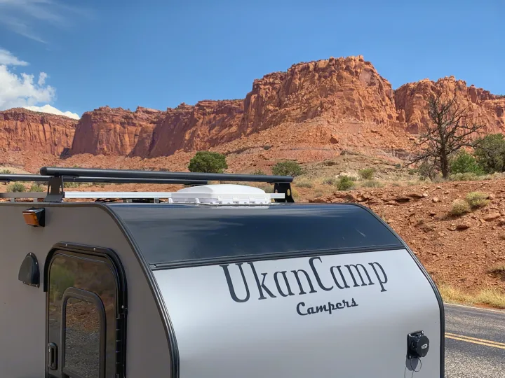 Teardrop RV rental from UkanCamp against majestic red rock cliffs, ideal for a scenic desert road trip.. Little Guy Other 2020