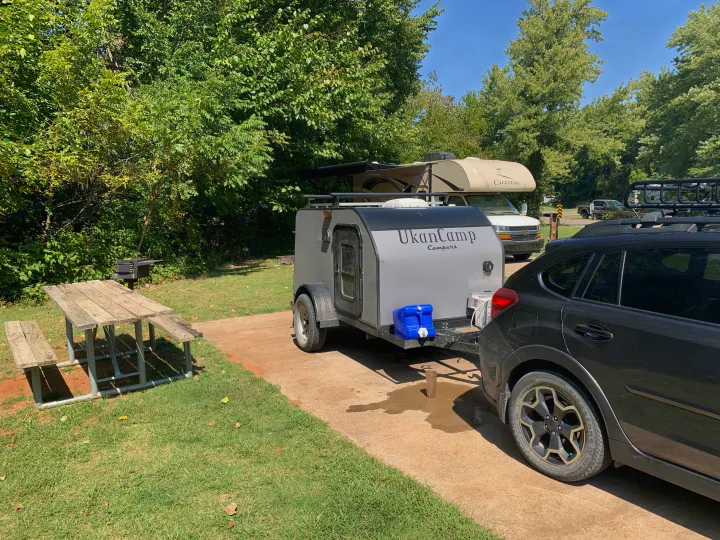 UkanCamp teardrop trailer, possibly an RV rental, hitched to an SUV at a campsite with picnic table and grill.. Little Guy Other 2020