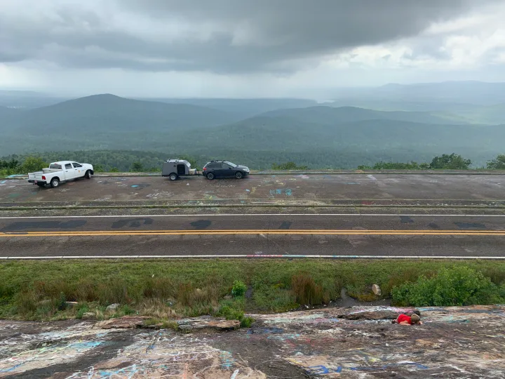 RV rental road trip: A teardrop camper and SUV are parked at a cloudy mountain overlook with a vast scenic view.. Little Guy Other 2020