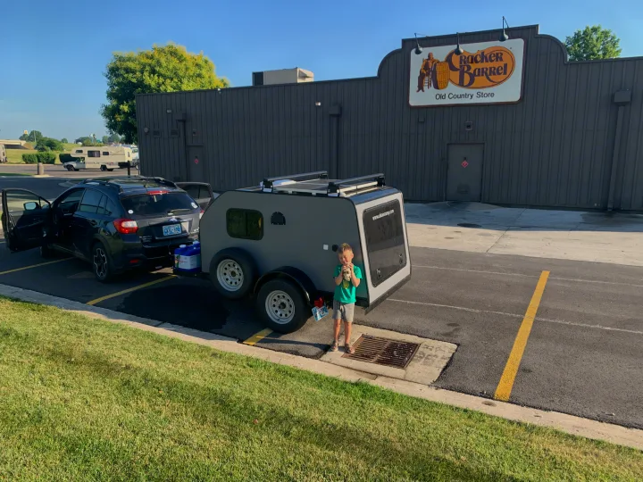 Subaru towing a teardrop camper at Cracker Barrel. Boy stands by camper. An RV is in background. Common stop for any RV rental.. Little Guy Other 2020
