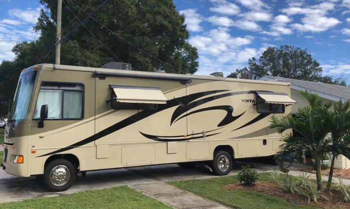 View of driver's side of RV.  Individual window awnings extended.  Dinette slide out not extended.. Winnebago Vista 32K 2010