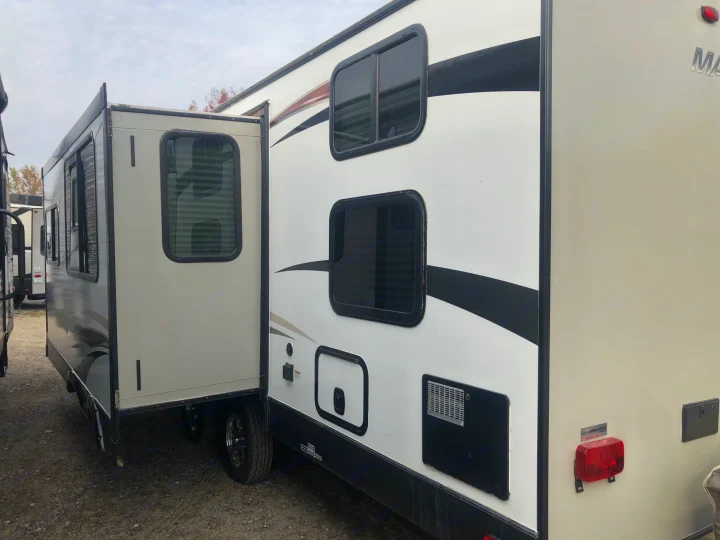 Side view of an RV rental with its slide-out extended, offering more living space. Features include windows and storage compartments.. Heartland M29 2017