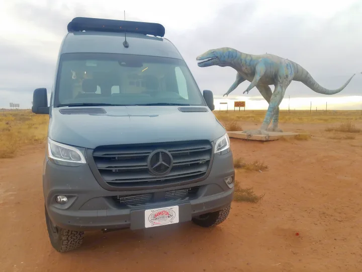 Mercedes-Benz Sprinter RV rental parked near a large dinosaur statue and 'GAS' sign in an arid landscape.. Winnebago Revel 2020