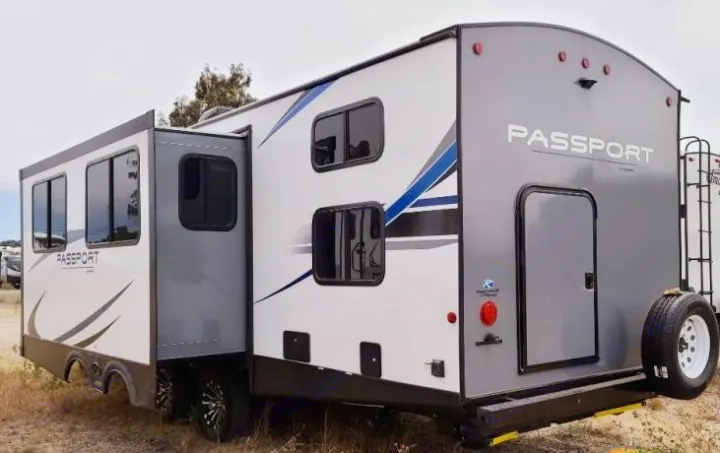 Exterior of a modern white & gray Passport travel trailer with slide-out extended, ideal for rv rental.. Keystone RV Passport GT 2021